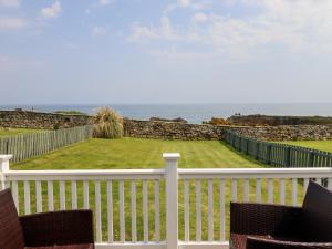 balcón con 2 sillas y vistas al océano en South Cottage Howick, en Craster