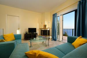 Nisos Sunset Apartments Agios Gordios في مدينة كورفو: غرفة معيشة مع أريكة زرقاء وطاولة زجاجية