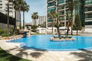 uma grande piscina azul com palmeiras numa cidade em Magic Atrium Beach em Cala de Finestrat