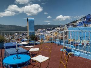 a balcony with chairs and tables and a view of a city at Hôtel Barcelona in Chefchaouen
