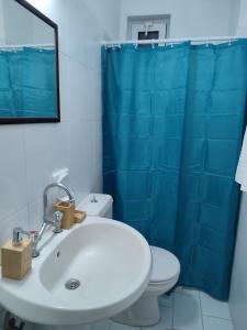 a bathroom with a white sink and a blue shower curtain at Dolphin Apartments in Faliraki