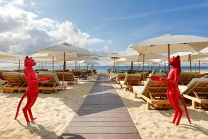 dos estatuas de gatos rojos en una playa con sillas y sombrillas en Ushuaia Ibiza Beach Hotel - Adults Only-Entrance to Ushuaia Club included, en Playa d'en Bossa