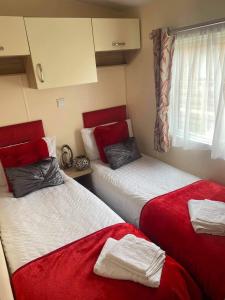 two beds in a room with red and white sheets at Kielder in Morpeth
