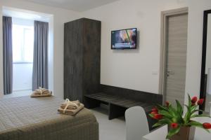1 dormitorio con 1 cama y TV en la pared en GEMMA DEI 2 MARI, en Cinquefrondi
