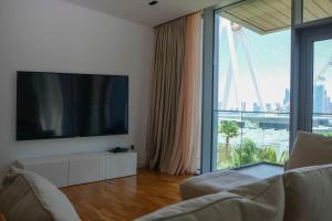 a living room with a tv and a large window at Mira Holiday Homes - Cozy apartment in Bluewaters in Dubai