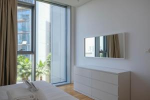 a white bedroom with a dresser and a mirror at Mira Holiday Homes - Cozy apartment in Bluewaters in Dubai