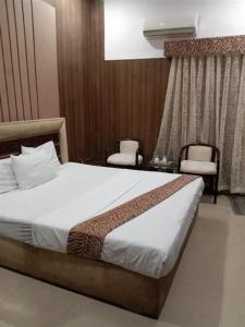 a bedroom with a large bed and two chairs at Helen One Hotel in Lahore