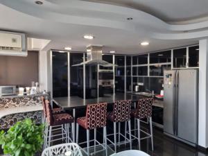 a kitchen with a counter with chairs and a refrigerator at The View Beach Penthouse in Limassol