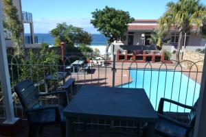 a patio with a table and chairs next to a swimming pool at Driftsands Sea View Flats in Uvongo Beach