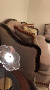 a couch with pillows and a lamp on a table at Classy Apartment in Buraydah