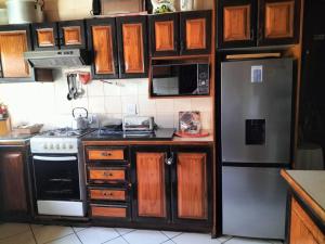 een keuken met houten kasten en een roestvrijstalen koelkast bij ADS Overnight Accommodation in Richards Bay