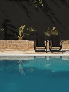 - deux chaises assises à côté de la piscine dans l'établissement Quomorari, à Barletta