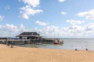 a beach with a pier and a boat in the water at Seaside Family Bungalow for 5 people with garden and driveway parking in Kent