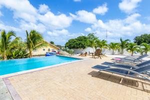 a swimming pool with lounge chairs next to a house at ABC Resort Curacao in Willemstad