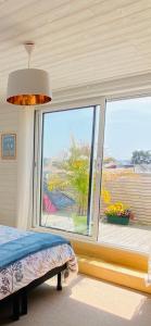 a bedroom with a bed and a large window at "le Skiff", bord de mer et spa, à la VILLA PLEIN VENT in Barneville-Carteret