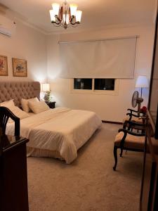 a bedroom with a bed and a chair and a window at شاليه La veranda in Durat  Alarous