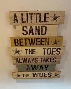 a sign that says a little sand between the toes always takes the woes at The Little Lighthouse - 2 minutes from the beach in Pentewan