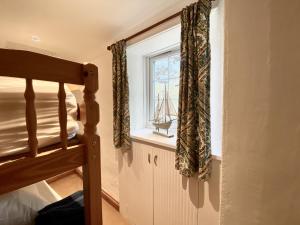 a bedroom with a bed and a window with a small boat on it at The Little Lighthouse - 2 minutes from the beach in Pentewan