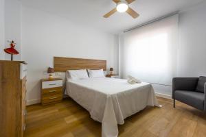 een slaapkamer met een bed, een plafondventilator en een stoel bij Apartamento Saint Louis I in Marbella