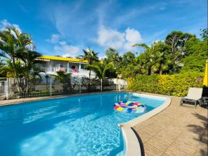 a swimming pool with a pool noodle in front of a house at Les Orchidées de Sainte-Anne in Sainte-Anne