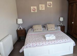 een slaapkamer met een wit bed en 2 nachtkastjes bij Les gîtes de Cour Rémond in Villers-la-Faye