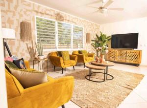 a living room with yellow chairs and a flat screen tv at Villa Bon Bon - Jan Thiel - Vista Royal in Jan Thiel