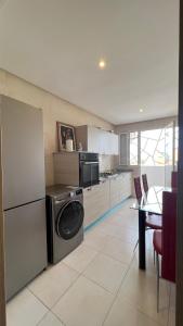 eine Küche mit einer Waschmaschine, einem Kühlschrank und einem Tisch in der Unterkunft Haut Standing Appartement - Centre Ville Oujda in Oujda
