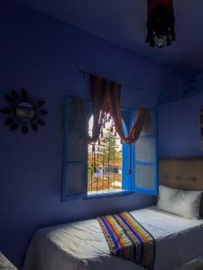 a bedroom with a blue wall with a window at Hôtel Barcelona in Chefchaouen