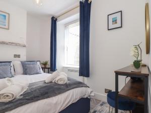 a bedroom with a bed with blue curtains and a window at The Oystercatcher in Falmouth