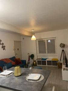 een woonkamer met een blauwe bank en een tafel bij ABSL Appartement in Villefranche-sur-Saône