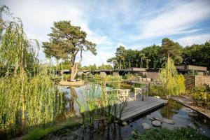 a wooden bridge over a pond with two chairs on it at Soof Heuvelrug in Rhenen