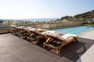 een rij ligstoelen naast een zwembad bij Sueno Villas in Panormos Rethymno