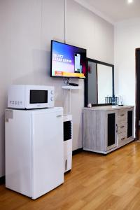 um quarto com um frigorífico branco e uma televisão em Airport Royal Guest House em Kempton Park