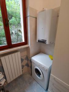 uma pequena casa de banho com uma máquina de lavar roupa e uma janela em Amalia by the Sea - Quercianella - Piano Terra em Case Fortullino