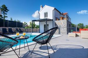 un patio con mesa y sillas junto a una piscina en Luxury 5 stars villa Berisha en Krk