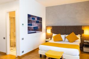 una camera d'albergo con letto con cuscini gialli di Hotel Como a Como