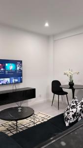 un soggiorno con 2 tavoli e una TV a schermo piatto di Neptun guest house a Queluz