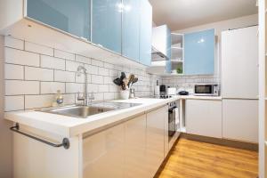 a kitchen with white cabinets and a sink at Calvin Street converted warehouse in London