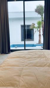 a bed in a room with a window and a palm tree at شاليهات بلاسيو 