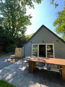 a large wooden table with chairs in front of a house at Leef Zuiden in Simpelveld