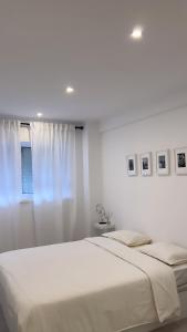 a white bedroom with a bed and a window at Neptun guest house in Queluz