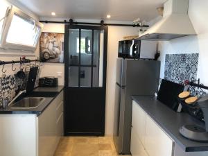 a kitchen with a black door and a refrigerator at Paris-Eiffel, bienvenue -terrasse -Netflix in Pantin