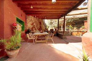un patio con mesa, sillas y pared de piedra. en La Casa del Molino de Viento en Agaete
