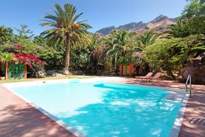 a swimming pool with palm trees and mountains in the background at La Casa del Molino de Viento in Agaete