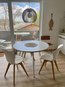 una mesa y sillas blancas en una habitación con ventana en Fewo Elena 150 m bis zum Strand, en Altefähr