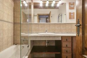 a bathroom with a sink and a tub and a mirror at Luderna - Apartamento Centelha in Tredós