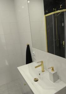 a white bathroom with a sink and a mirror at Apartament Magnolia in Muszyna