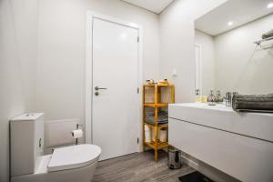 a white bathroom with a toilet and a sink at Solar da Rochinha Magnifico Apt 2 Quartos Funchal in Funchal