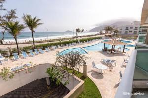 a resort with a pool and chairs and the beach at Unidade Autonoma 609 em Villa Del Sol in Rio de Janeiro