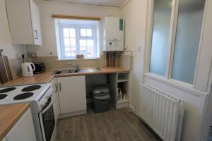 a small kitchen with white cabinets and a sink at Flat 2 @ 28 Chilkwell Street in Glastonbury